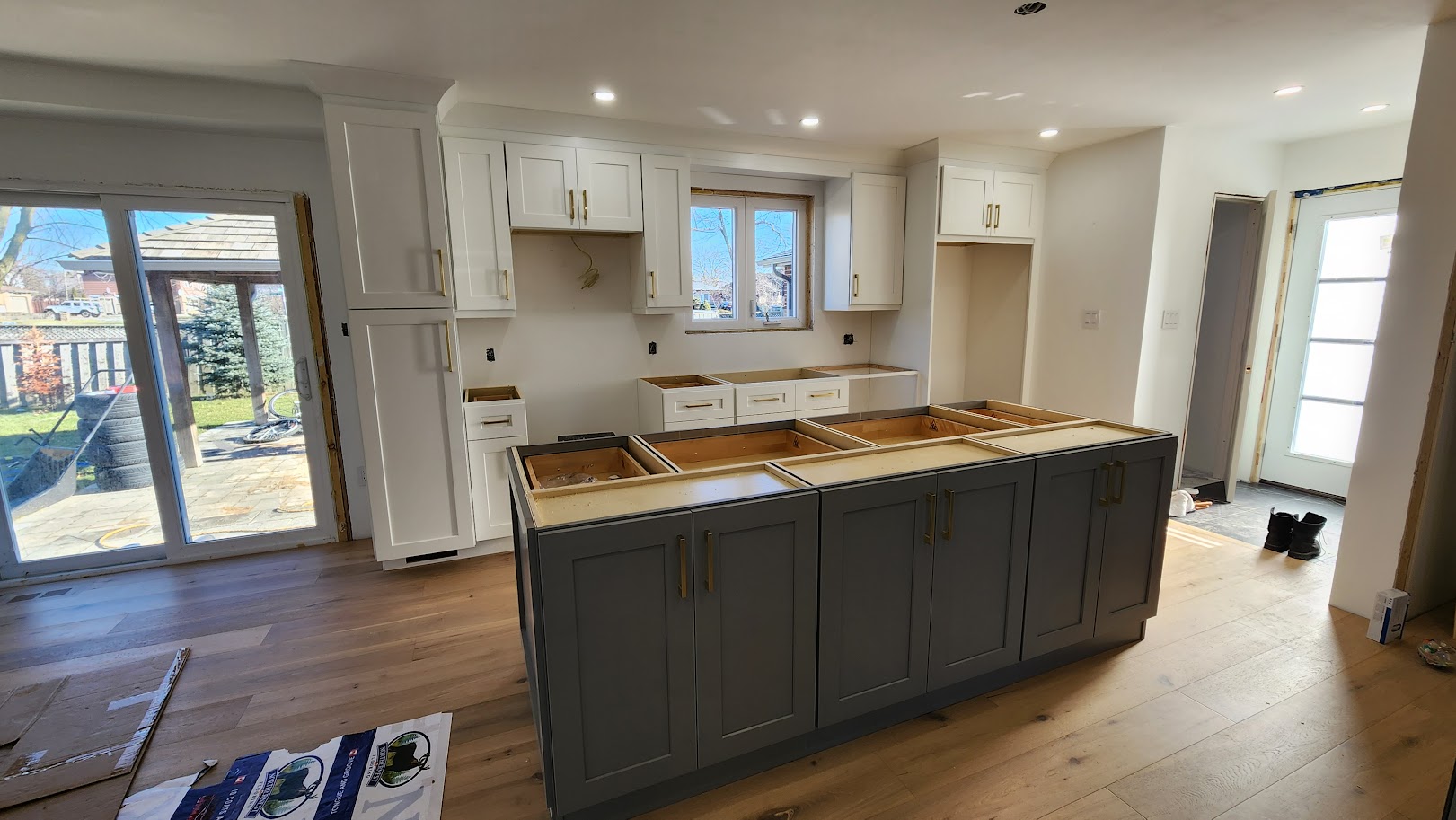 Brampton kitchen during cabinet installation with white perimeter cabinets and a grey island, before countertops
