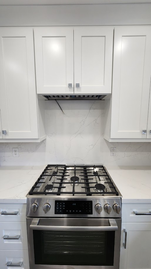 North York kitchen after update with white shaker cabinets, range hood and light veined backsplash
