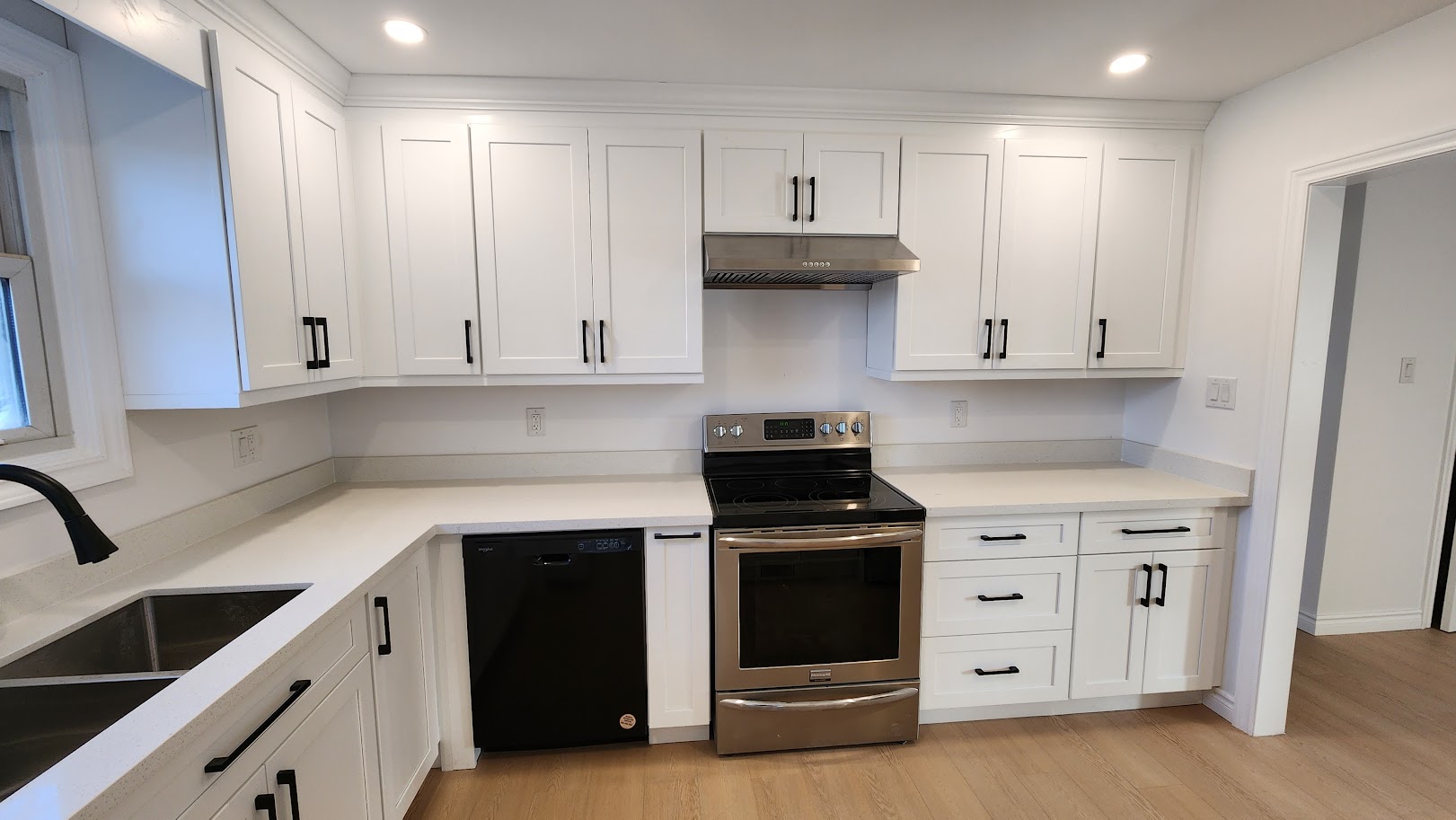 Upper-unit kitchen after update with white shaker cabinets, dark pulls and light counters