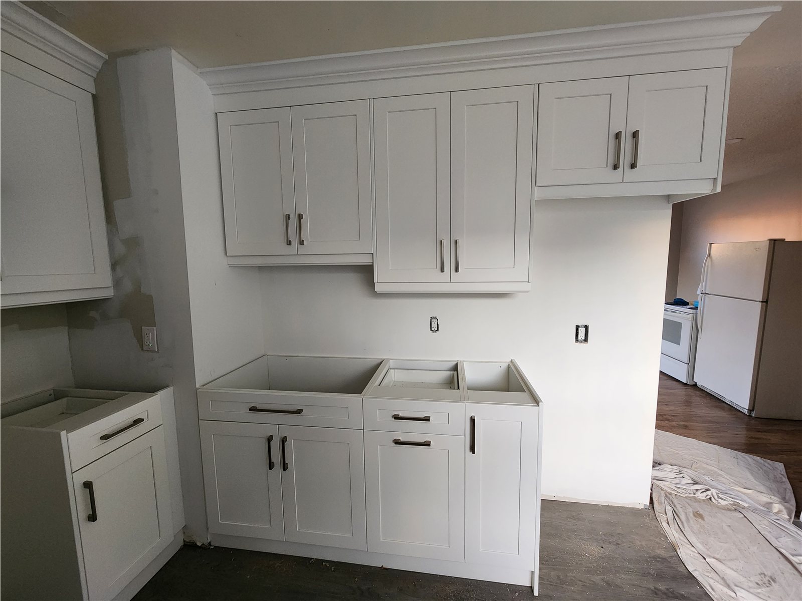 Whitby kitchen during white shaker cabinet installation with unfinished appliance openings